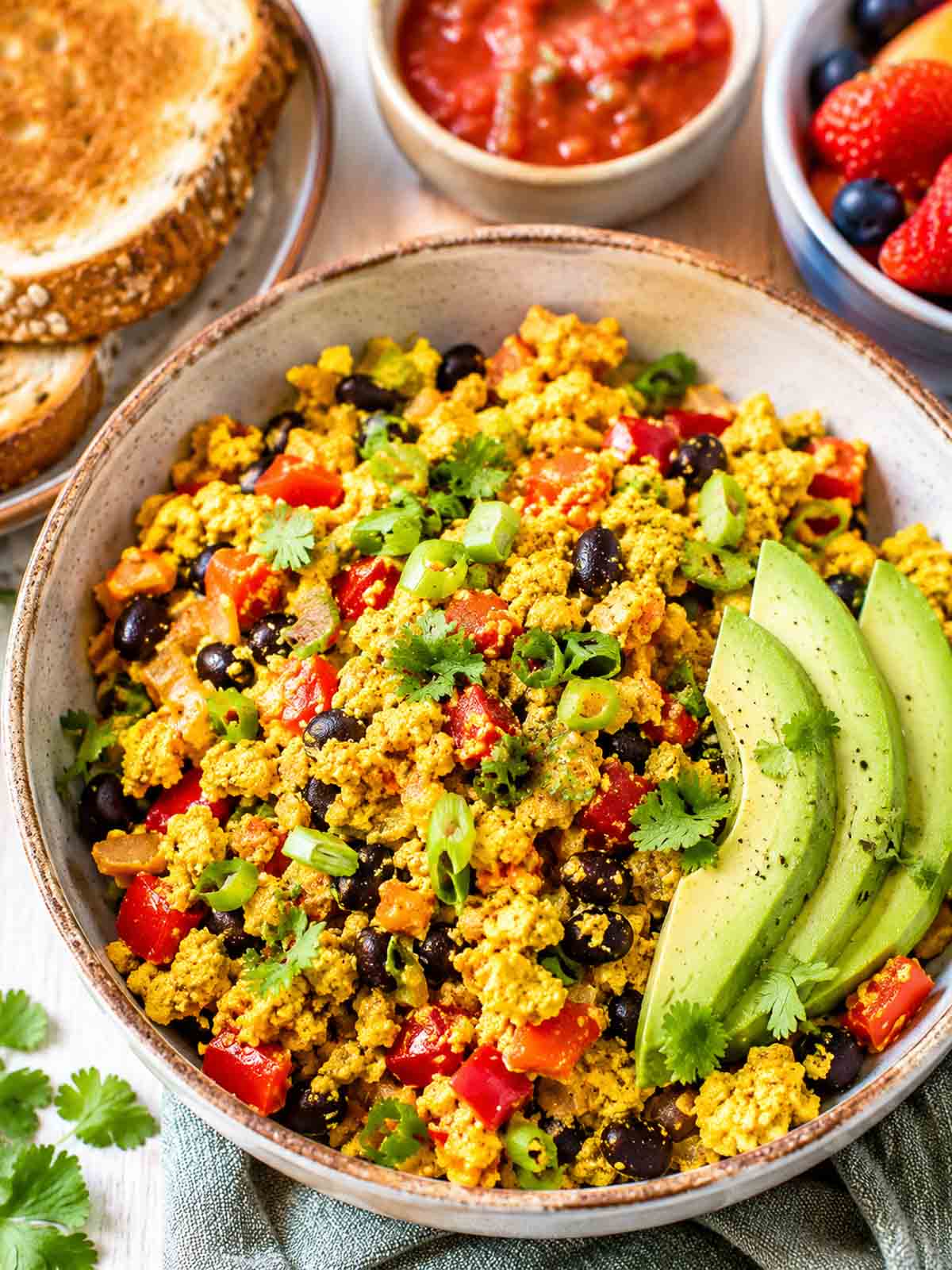 big bowl filled with loaded tofu scramble with avocado slices.