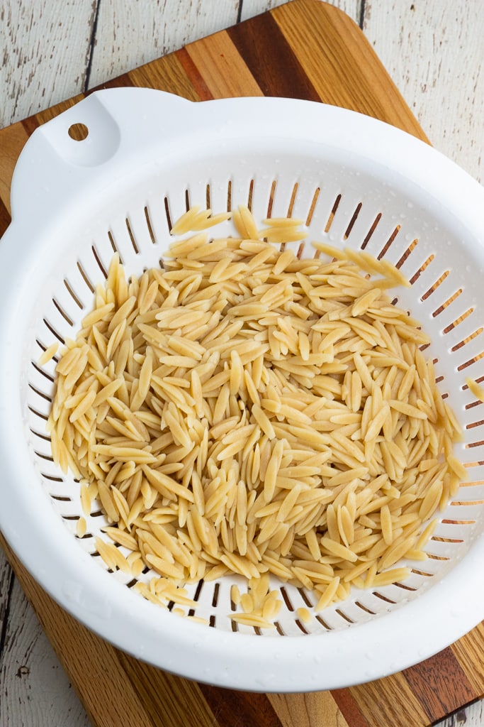 white colander with freshly cooked whole wheat orzo pasta
