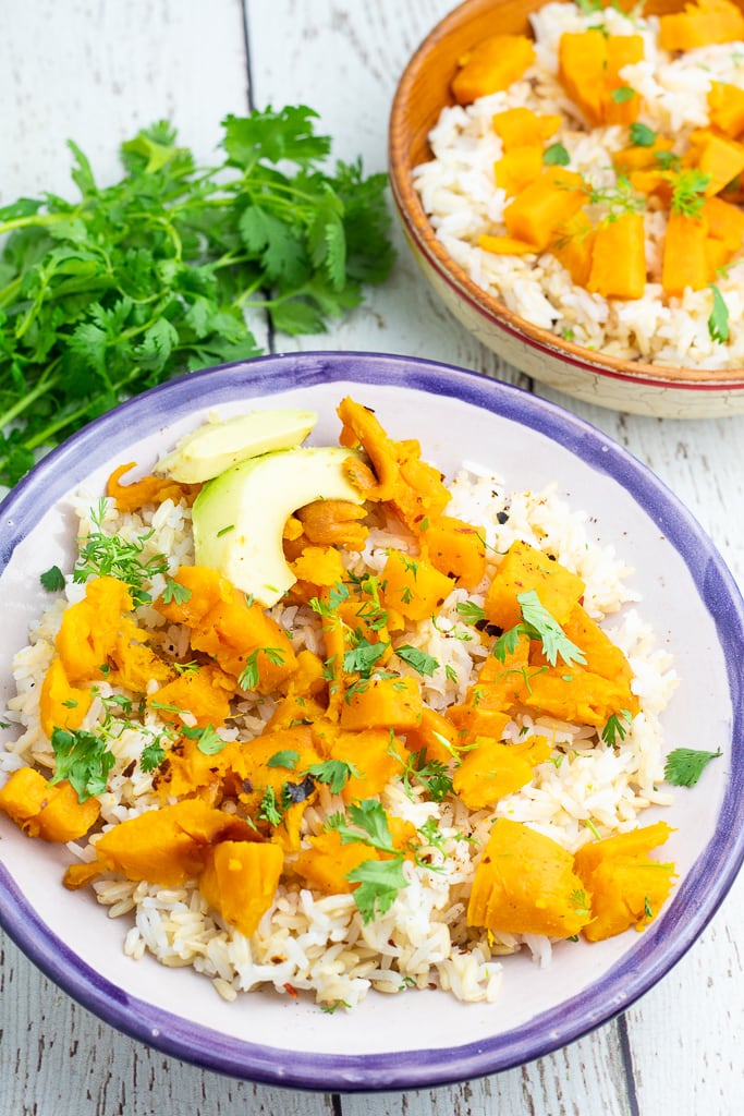 blue rimmed bowl of sweet potatoes and rice with avocado and cilantro