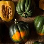 collection of whole acorn squash on burlap in dark lighting