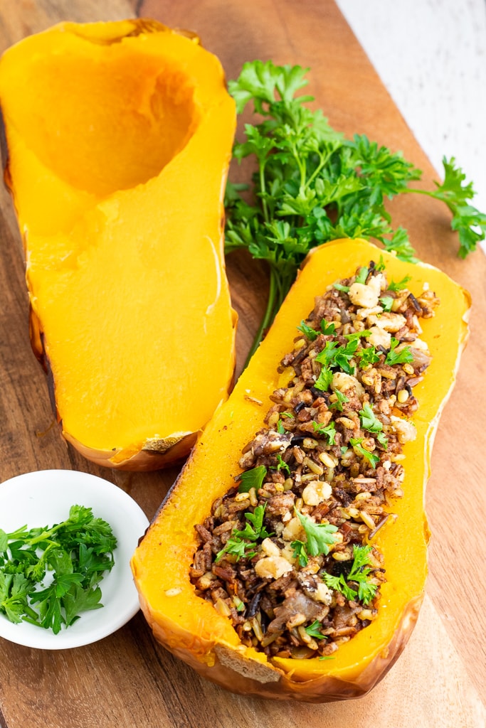 2 halves of a baked butternut squash one is stuffed with rice and one plain