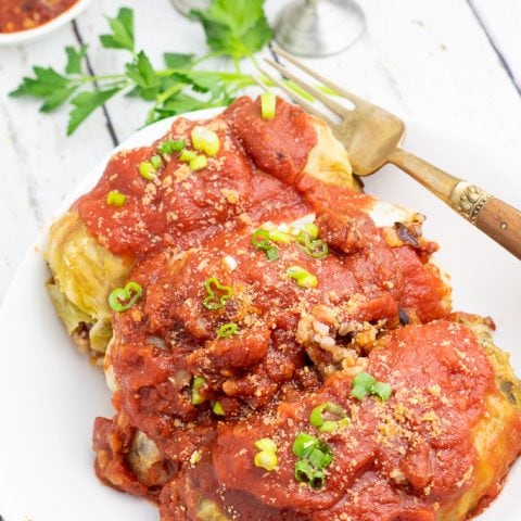white plate with 3 healthy stuffed cabbage rolls with fork