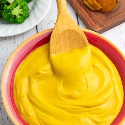 colorful red and yellow bowl filled with sweet potato cheese sauce