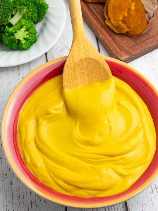 colorful red and yellow bowl filled with sweet potato cheese sauce