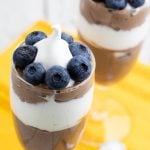 two fancy stemmed glasses full of chocolate mousse and whipped cream