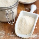 white scoop filled with homemade powdered sugar on wood board
