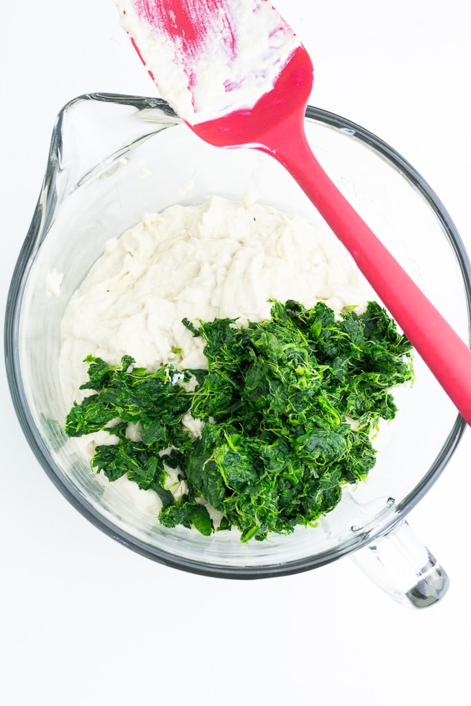 glass mixing bowl with cashew sauce and spinach