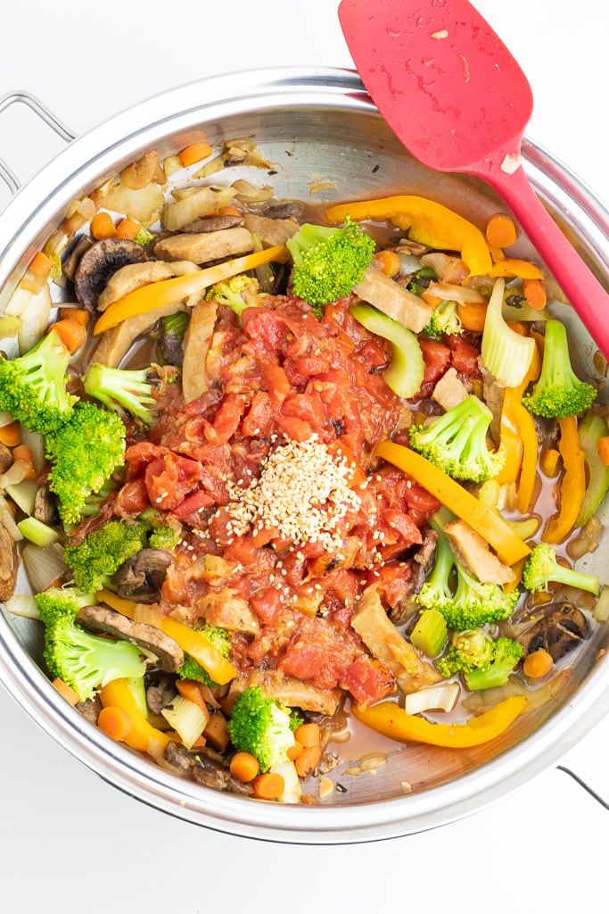 wok filled with broccoli, carrots, bell pepper, onions, tomatoes
