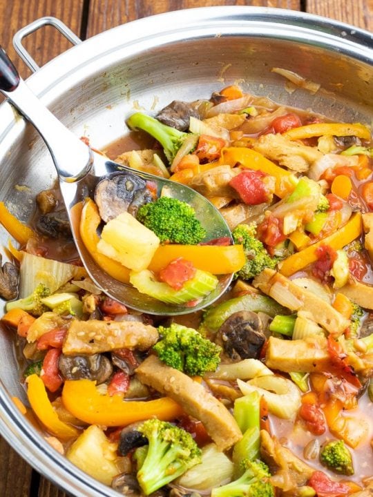 close up of sweet and sour vegan stir fry in wok with spoon