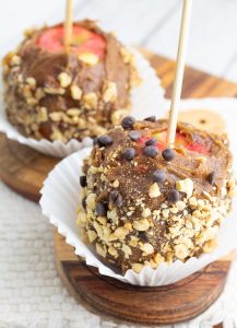 vegan caramel apples covered in peanuts and chocolate chips