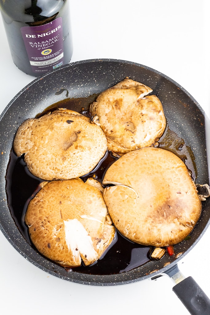 large portobello caps in pan with balsamic vinegar