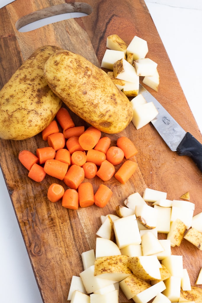 wooden cutting board with diced potatoes and carrots