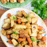 white platter with roasted potatoes and carrots on wooden board