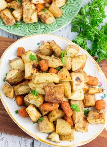 white platter with roasted potatoes and carrots on wooden board