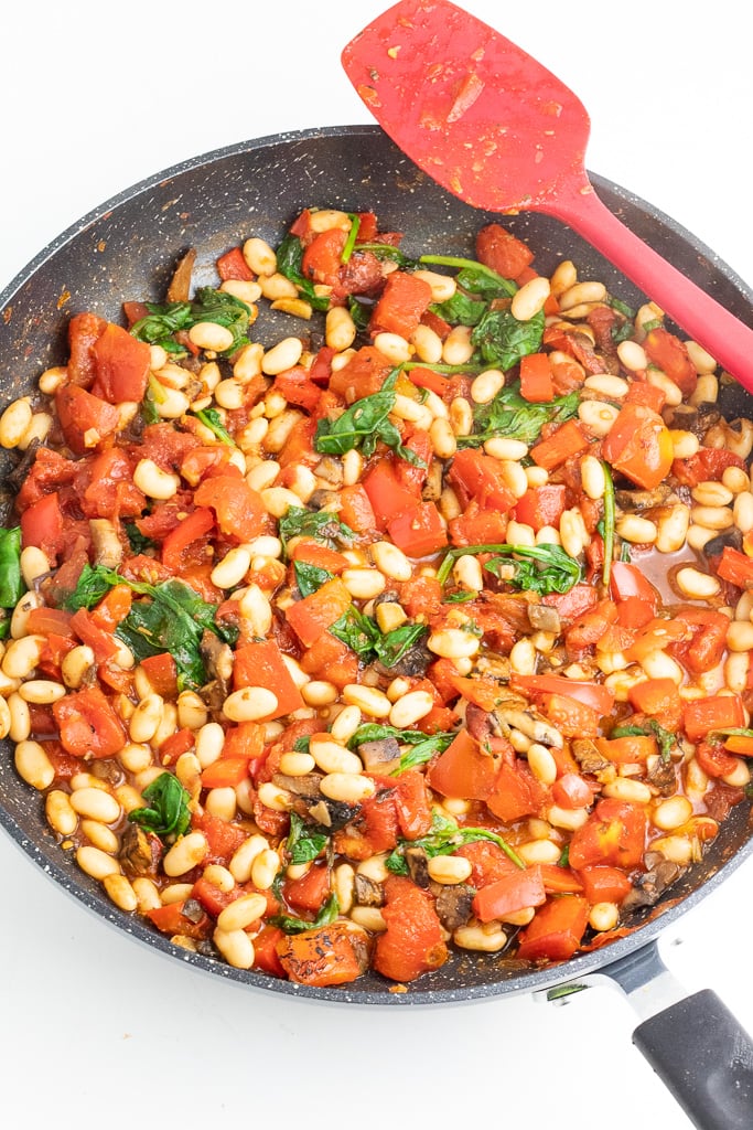 sautee pan with beans, mushrooms, spinach, tomatoes