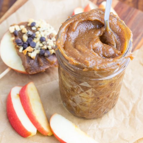vegan caramel in small glass jar with spoon and apple slices