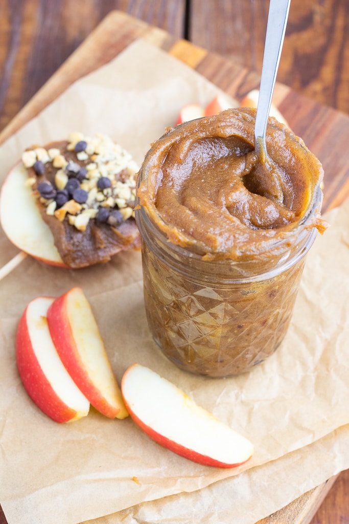 vegan caramel in small glass jar with spoon and apple slices