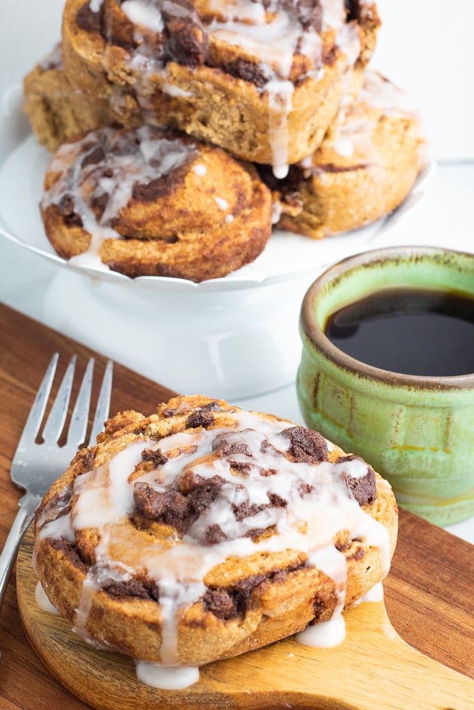 cinnamon roll on wooden board with fork and coffee