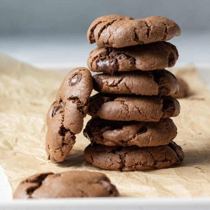 vegan double chocolate cookies stacked up on brown paper