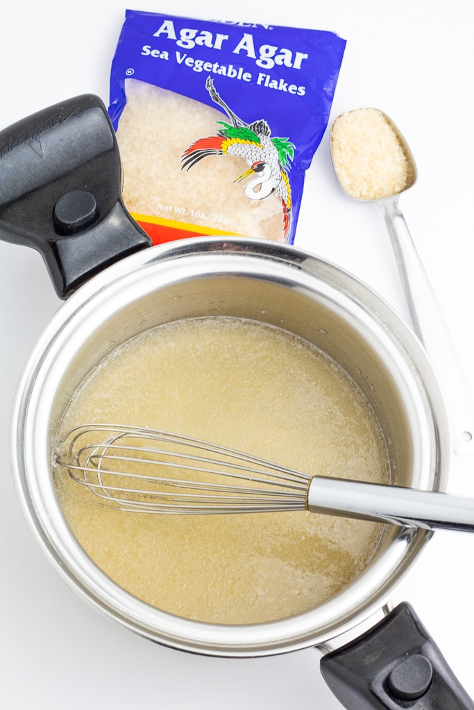 Agar Agar flakes being boiled in stainless saucepan with whisk and package