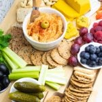 vegan charcuterie board with hummus, crackers, vegan cheese, fruit, veggies, olives, pickels