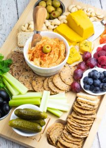 vegan charcuterie board with hummus, crackers, vegan cheese, fruit, veggies, olives, pickels