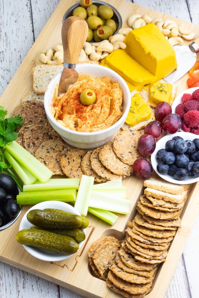 vegan charcuterie board with hummus, crackers, vegan cheese, fruit, veggies, olives, pickels