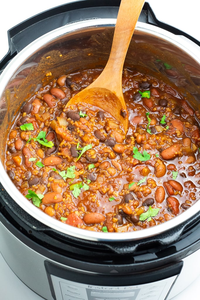 vegan instant pot full of chili with wooden spoon scooping