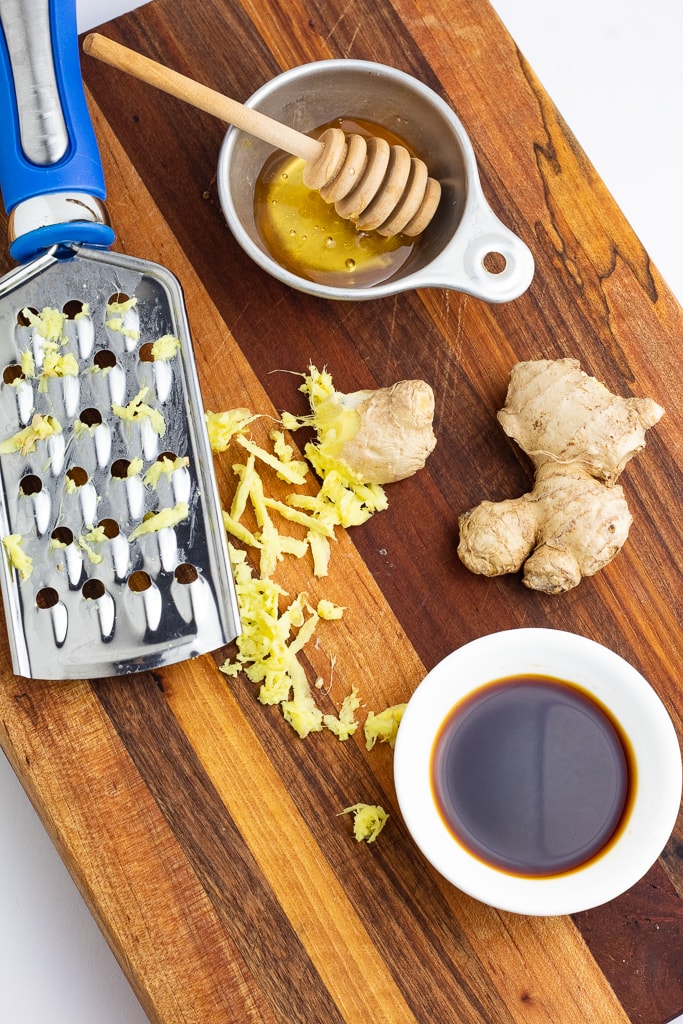 wood cutting board with grated ginger, honey, and soy sauce