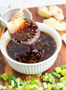 white bowl with spoonful of teriyaki sauce on wooden board