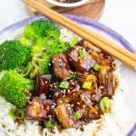 bowl filled with rice and tofu teriyaki with broccoli and chopsticks