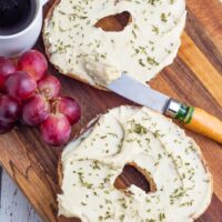 2 bagel halves smeared with vegan cashew cream cheese with grapes and coffee