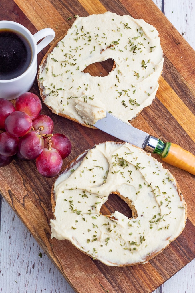 2 bagel halves smeared with vegan cashew cream cheese with grapes and coffee