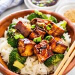 wooden bowl of brown rice topped with tofu teriyaki and broccoli.