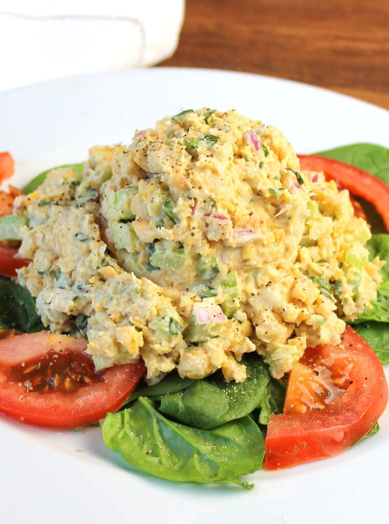 chickpea tuna salad on a bed of fresh spinach and sliced tomatoes
