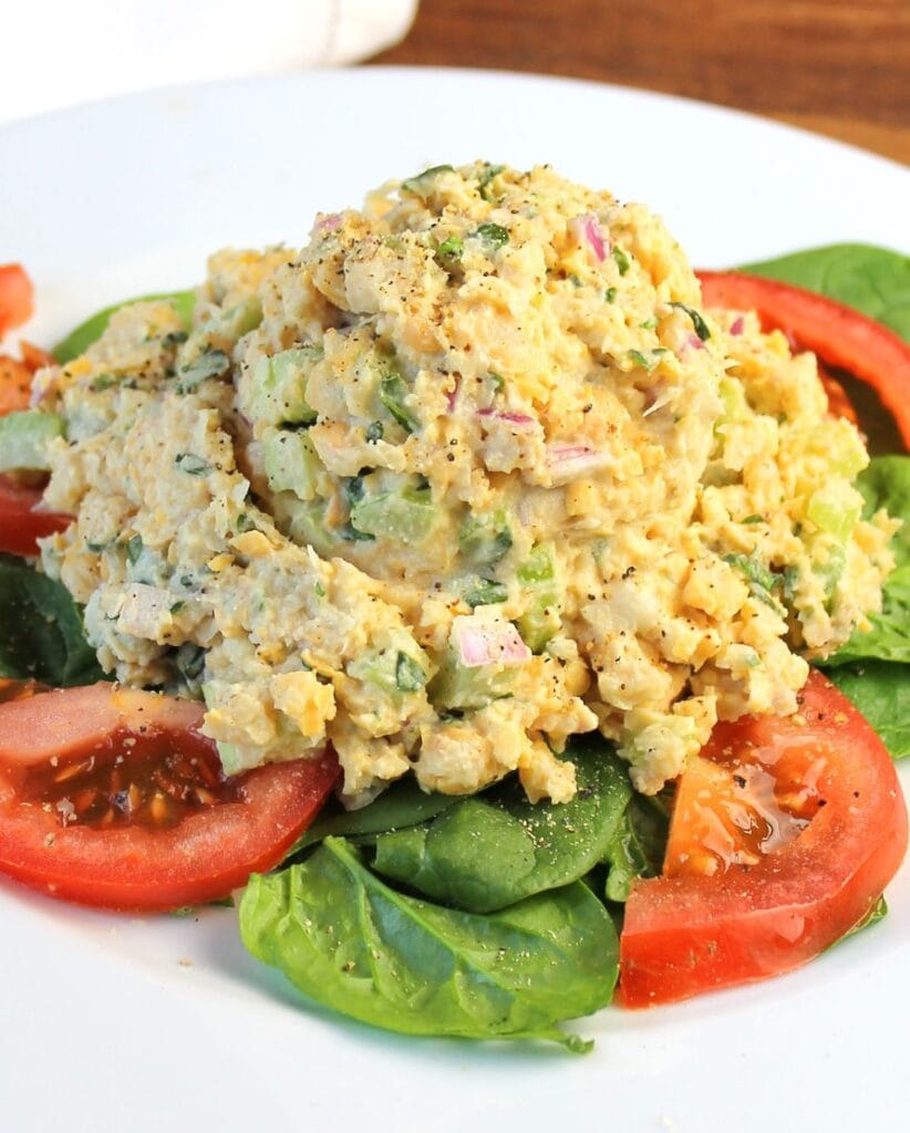 chickpea tuna salad on a bed of fresh spinach and sliced tomatoes