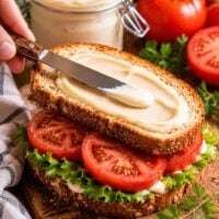 tofu mayo being smeared on a tomato sandwich.