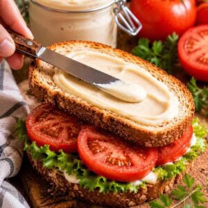 tofu mayo being smeared on a tomato sandwich.