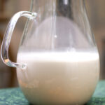 homemade almond milk in glass pitcher half full
