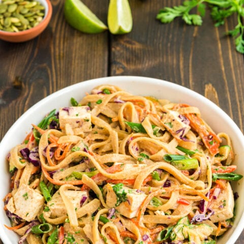 vegan pad thai on white plate and wooden tabletop
