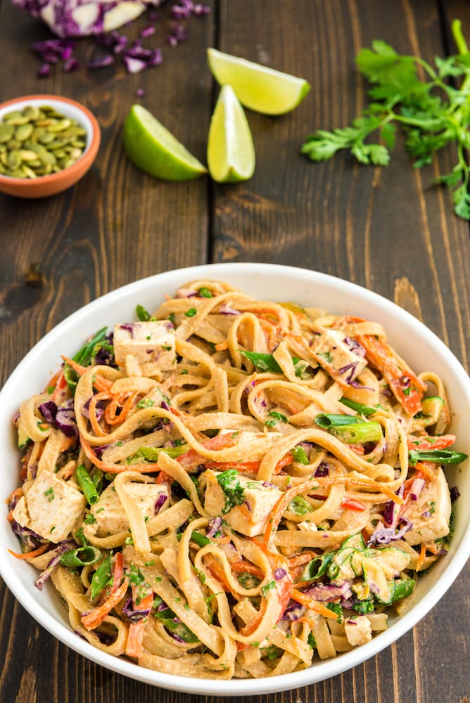 vegan pad thai on white plate and wooden tabletop