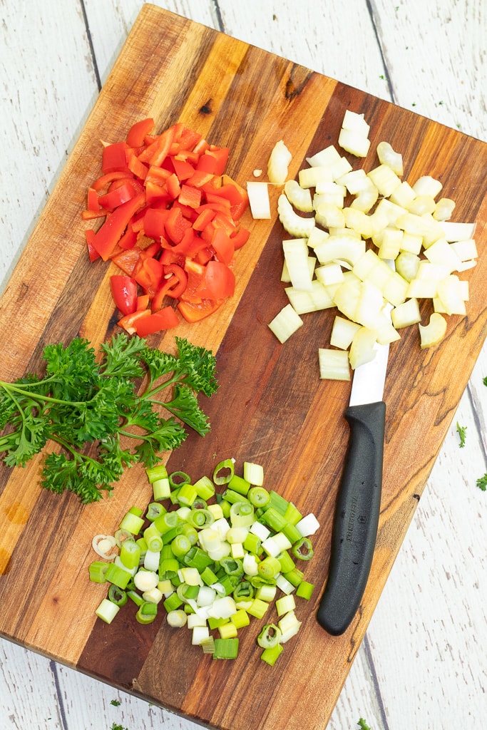 green onions, celery, bell pepper, and parsley chopped on cutting board