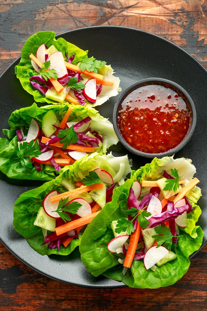 Vegetable lettuce wraps with carrot, onion, radish, red cabbage, cucumber and sweet chilli sauce.