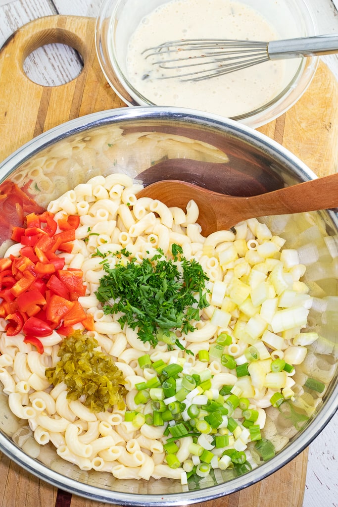 large mixing bowl with cooked elbow macaroni, diced onions, red bell pepper, relish