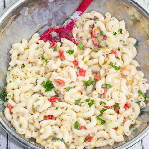 overhead shot of large mixing bowl full of vegan macaroni salad with red spoon