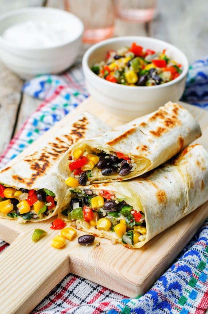 pepper corn black bean quinoa burritos on a white wood background. the toning. selective focus