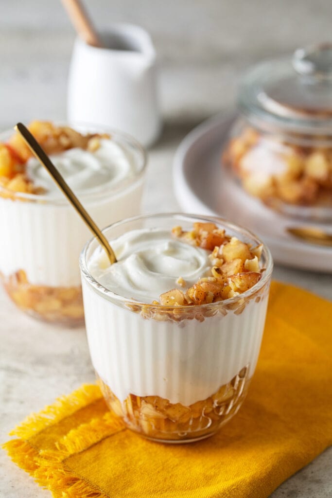 dairy free yogurt in dessert dishes with cinnamon, apple, and walnuts