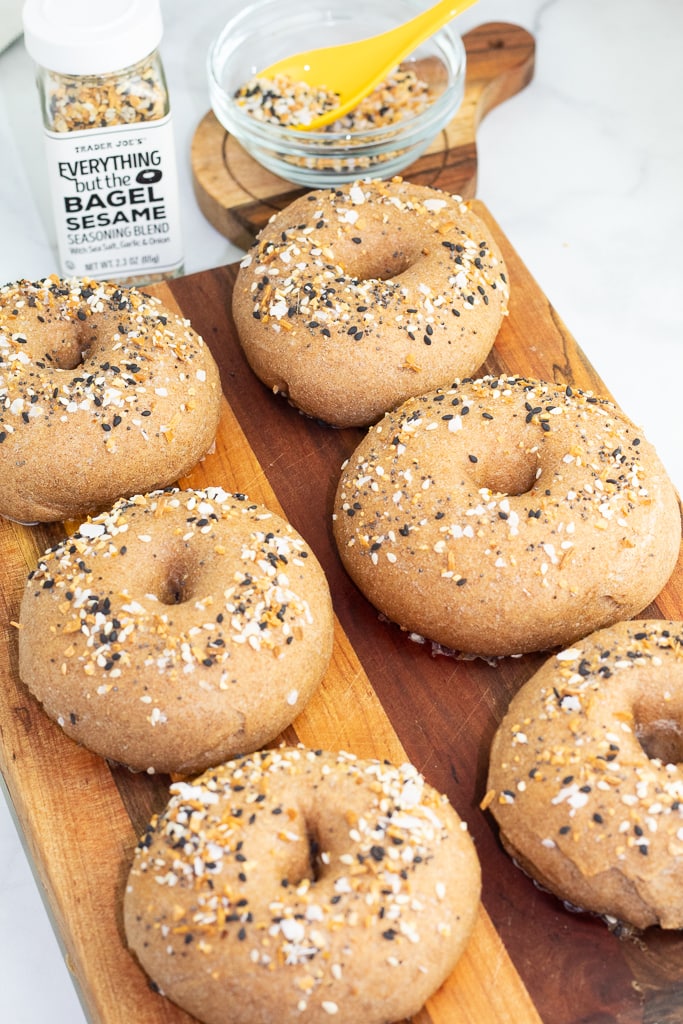 whole wheat bagels on wooden cutting board and sprinkled with everything but the bagel seasoning