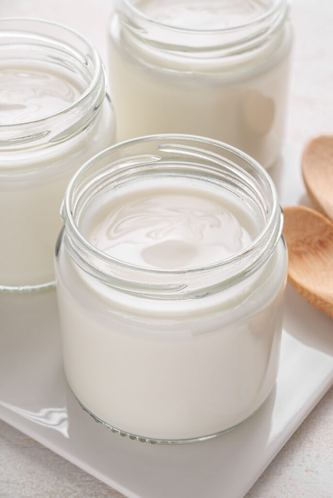 uncooked vegan yogurt in jars on white background
