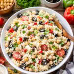 pasta salad with chickpeas, black olives, tomatoes, bell peppers, parsley, and creamy dressing.